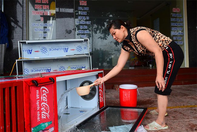 Chị Nguyễn Thị Thuỷ xách nước cọ rửa tủ lạnh sau khi thu dọn những chai nước vỡ.