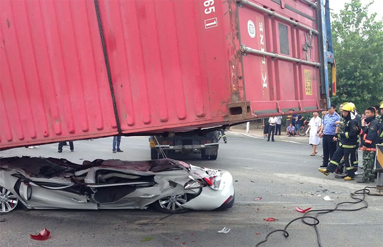 Một xe đầu kéo bị lật làm rơi container đè bẹp dúm chiếc ôtô con bên cạnh ở Thanh Đảo, Trung Quốc 