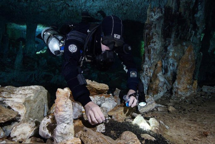 Một nhà khảo cổ đang lặn vào hang động để nghiên cứu