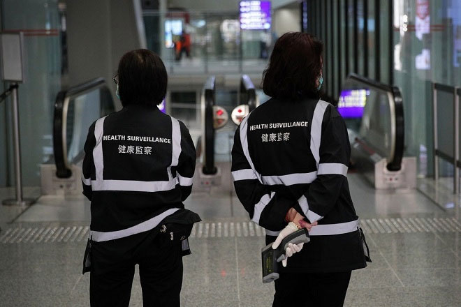 Đội giám sát y tế bằng máy đo nhiệt độ cơ thể ở sân bay Hong Kong.