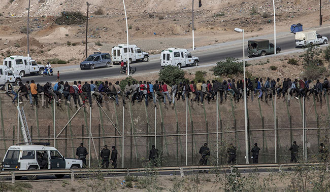 Cảnh sát dân sự (Guardia) Tây Ban Nha theo dõi những người nhập cư từ châu Phi ngồi trên hàng rào biên giới 