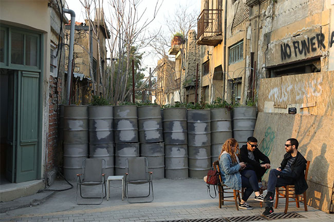 Một số người ngồi uống cà phê bên cạnh ranh giới được gia cố ở vùng đệm phía nam thuộc Hy Lạp