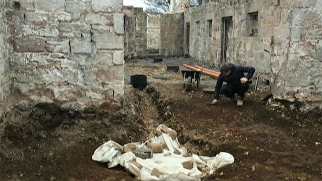 Một nhà khảo cổ đang tìm kiếm các hiện vật khác ở khu vực xung quanh hố chôn