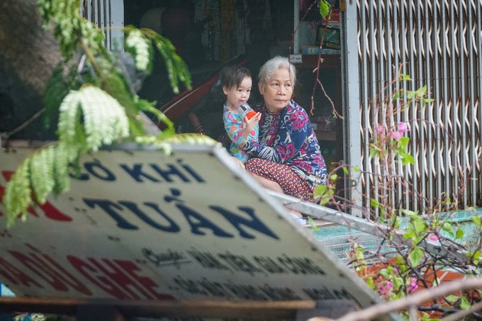 Hai bà cháu ôm nhau nhìn cây cối, bảng hiệu đổ sập trước nhà tại phường Hải Cảng.